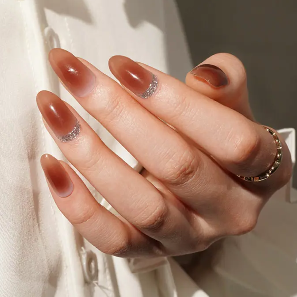 Ongle en gel KRISTEN caramel ombré avec accents pailletés : main présentée dans une lumière naturelle