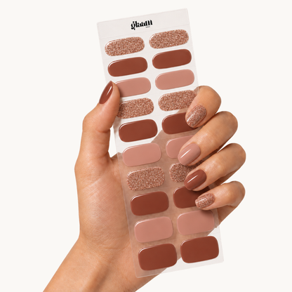 Ongle en gel MARISSA brun, nude rosé et paillettes cuivrées : main tenant la plaquette de bandes